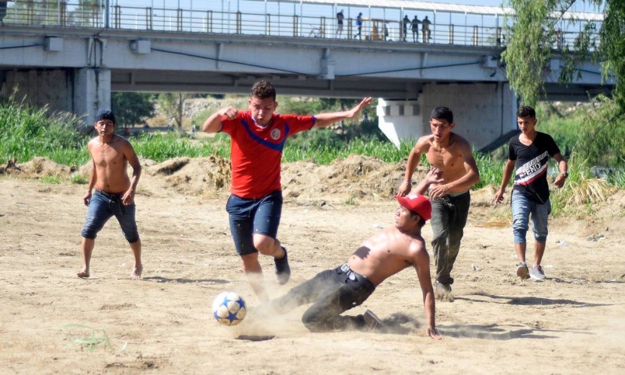 Um grupo que faz parte da caravana joga futebol na margem do rio Suchiate, em Tecun Uman, na Guatemala Foto: JOHAN ORDONEZ / AFP