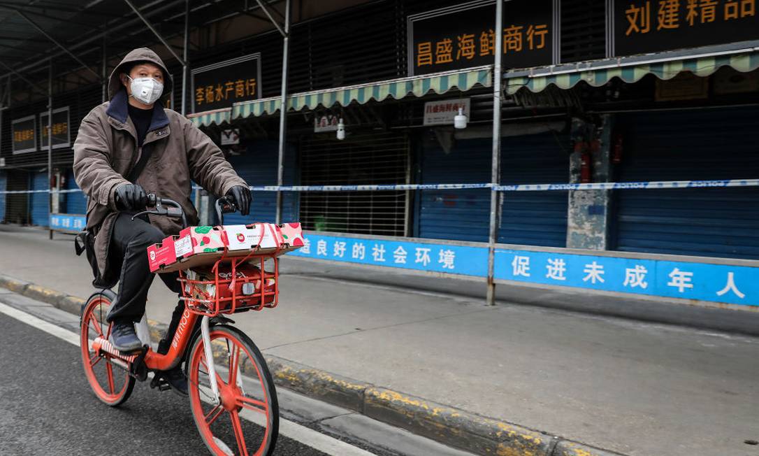 Ciclista pedala em frente ao Mercado Atacadista de Frutos do Mar de Huanan, na China. Foto: Getty Images