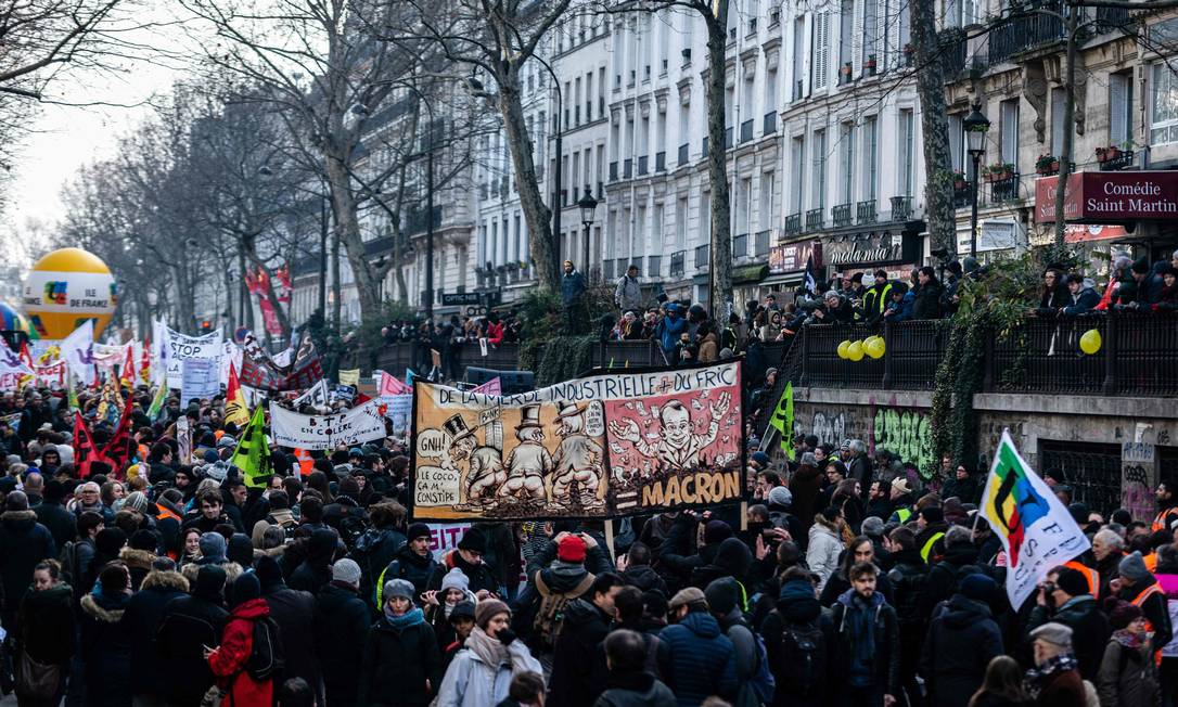 People hold a banner bearing drawings mocking French President Emmanuel Macron as they take part in a demonstration in Paris on January 24, 2020, as part of a nationwide multi-sector strike against the French government's pensions overhaul. (Photo by - / AFP) Foto: - / AFP