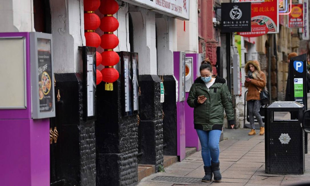 Mulher usa máscara facial enquanto caminha no distrito da cidade chinesa de Manchester, norte da Inglaterra. Desde seu surgimento em dezembro do ano passado, o coronavírus já se espalhou pela Ásia, Europa Estados Unidos e Austrália Foto: PAUL ELLIS / AFP