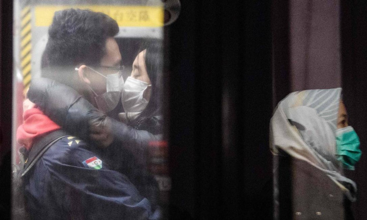 Um casal de máscaras faciais se beija em trem do metrô em Hong Kong Foto: ANTHONY WALLACE / AFP
