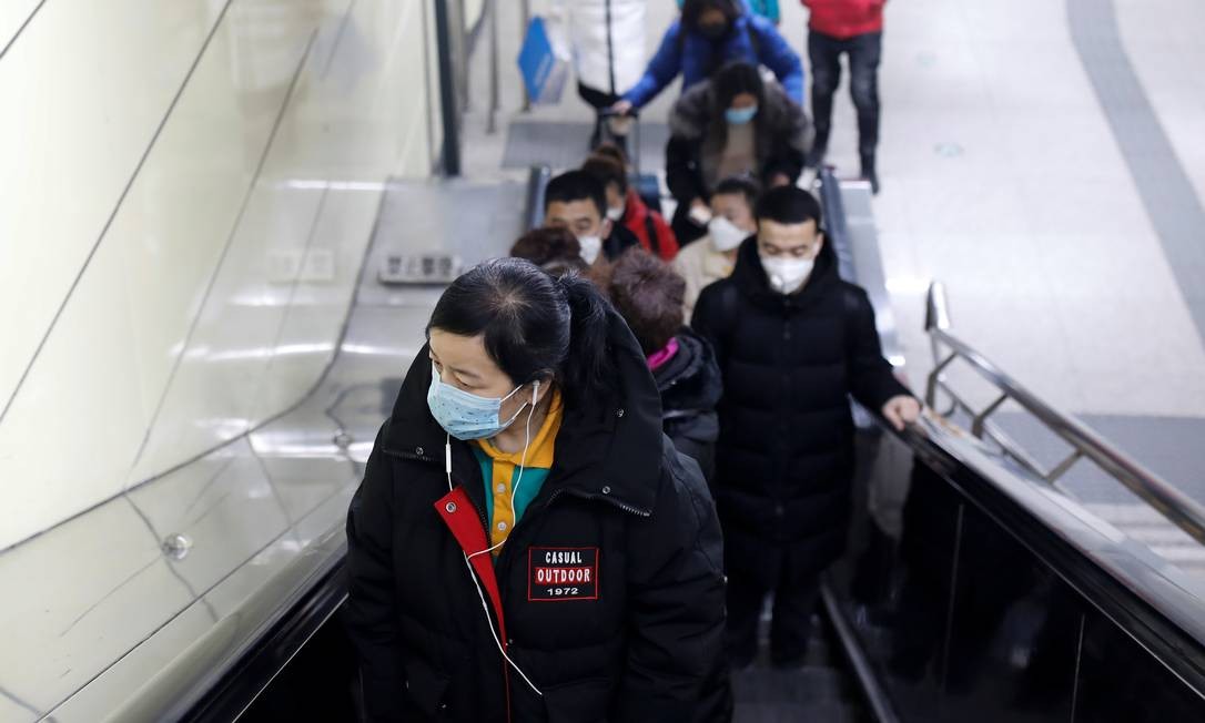Pessoas usam máscaras de proteção na escada da estação de metrô de Pequim, na China. Foto: CARLOS GARCIA RAWLINS / REUTERS