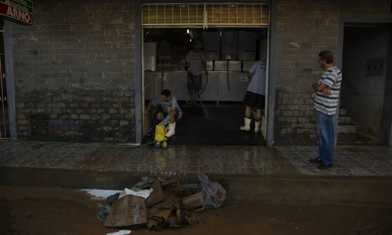 Funcionários limpam lama que invadiu loja de manutenção de refrigeradores, devido ao alagamento do Rio Muriaé, no centro de Itaperuna Foto: Gabriel Monteiro / Agência O Globo