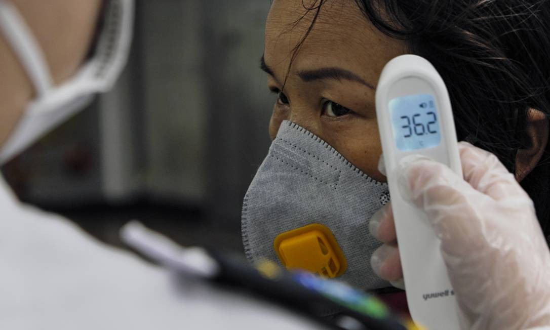 Uma mulher tem sua temperatura testada pelo segurança de uma estação do metrô. Guangzhou, China Continental, 25 de janeiro de 2020. Foto: Diego Herculano / Agência O Globo