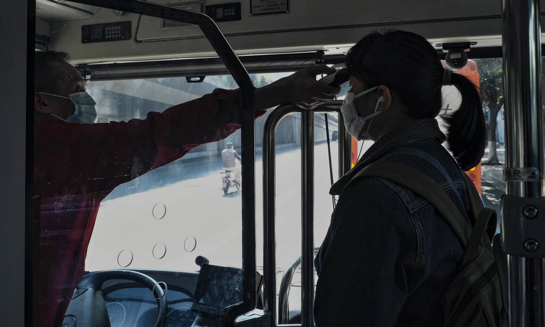 Uma passageira tem a temperatura do corpo medida pelo motorista de ônibus da cidade de Guangzhou, China Continental, 30 de janeiro de 2020. Foto: Diego Herculano / Agência O Globo