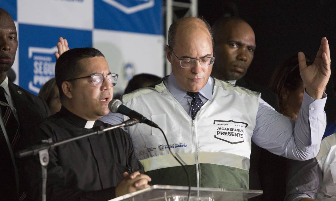 O governador Wilson Witzel rezando ao lado de um padre durante o evento Foto: Guito Moreto / Agência O Globo
