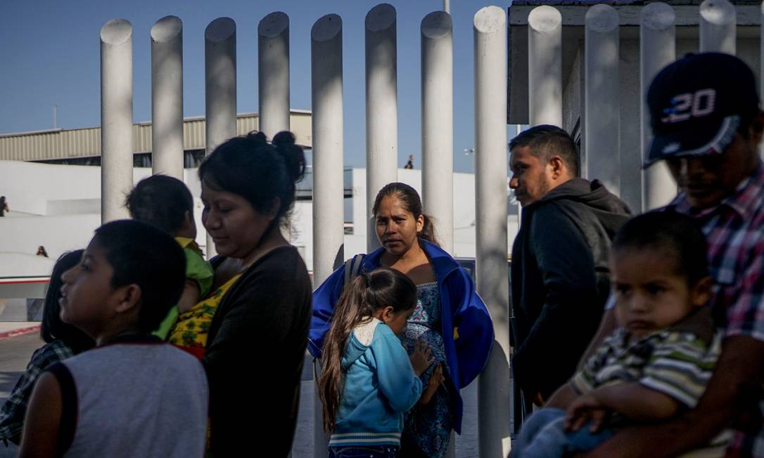 Hondurenhos esperam na fronteira do México, em Tijuana, para atravessar para os EUA Foto: SANDY HUFFAKER / AFP