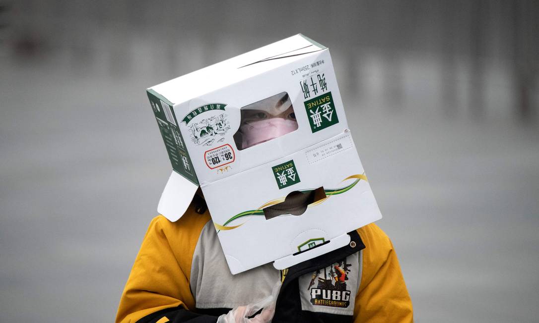 Garoto se protege com máscara e uma caixa de papelão nos arredores da estação ferroviária de Xangai Foto: NOEL CELIS / AFP