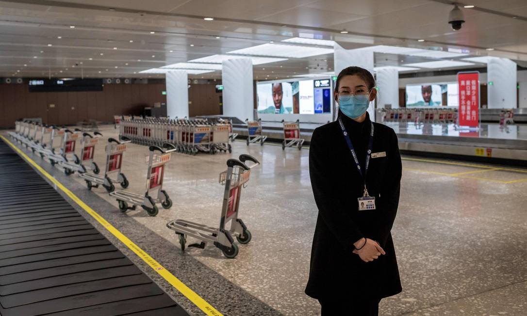 Após restrições a viagens, funcionária do aeroporto internacional de Pequim observa esteiras de devolução de bagagens vazia Foto: NICOLAS ASFOURI / AFP / 14-02-2020
