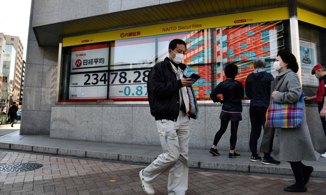 Pedestres usam máscaras de proteção em Tóquio. A capital japonesa deve cancelar eventos abertos para conter o coronavírus Foto: KAZUHIRO NOGI / AFP