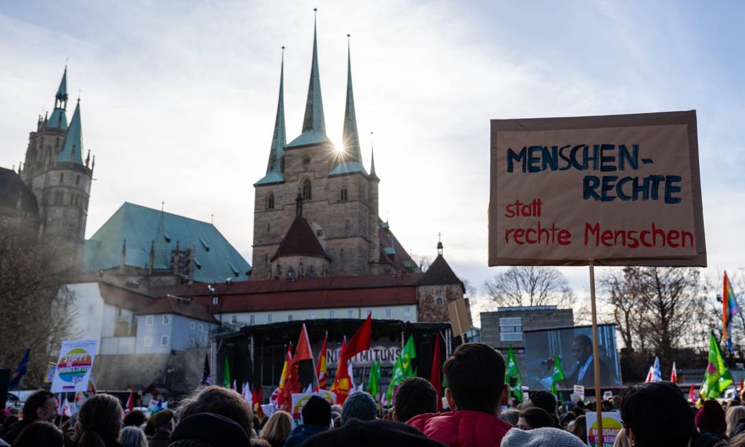 Com um cartaz onde se lê “Direitos humanos em vez do pessoal da extrema direita”, alemães protestam em Erfurt, capital da Turíngia, contra a aliança da CDU e FDP com a AfD Foto: JENS SCHLUETER/AFP/15-2-2020
