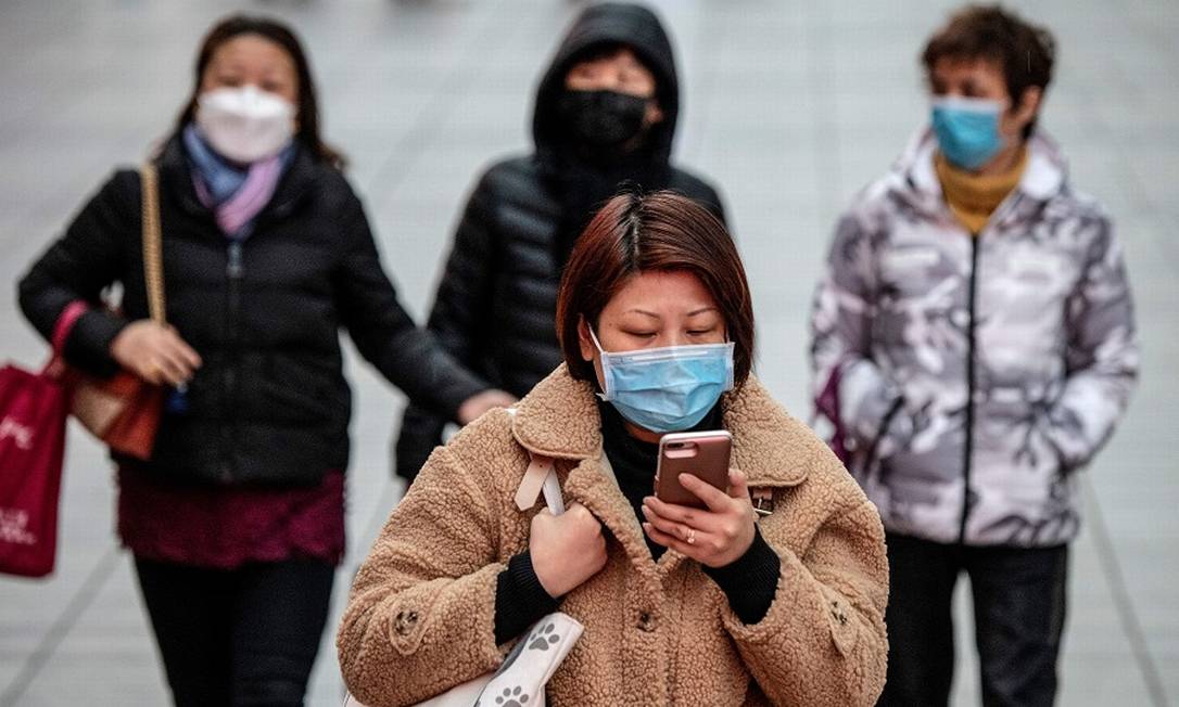 Transeuntes com máscaras cirúrgicas em Xangai: coronavírus afeta economia internacional. Foto: NOEL CELIS / AFP