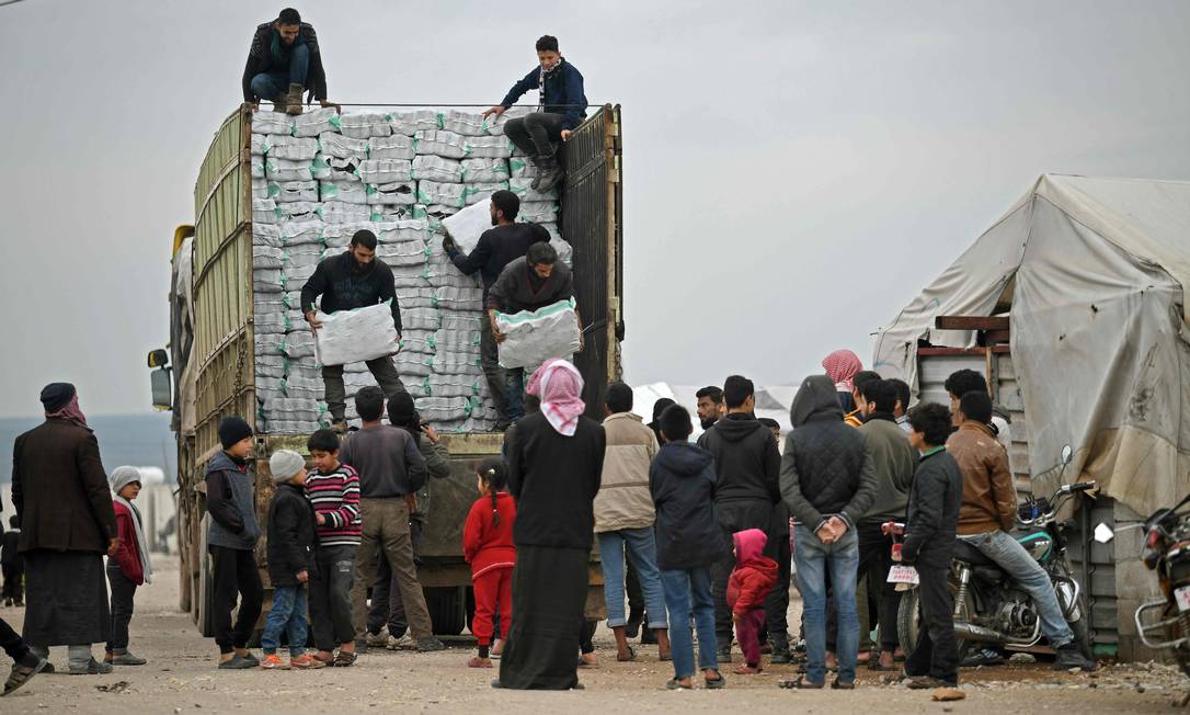 Refugiados sírios fazem fila para receber ajuda humanitária no campo de Mehmediye, perto da fronteira com a Turquia Foto: RAMI AL SAYED / AFP/21-2-2020