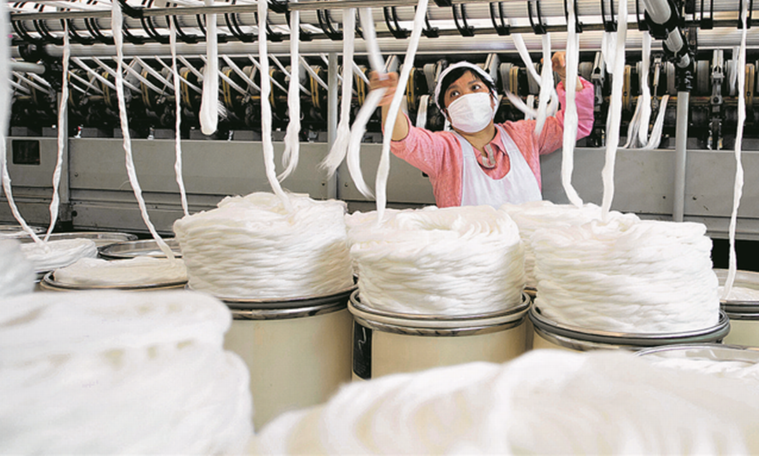 Funcionária em fábrica têxtil em Haian, na China: surto criou grande problema para empresas. Foto: China Daily / Reuters