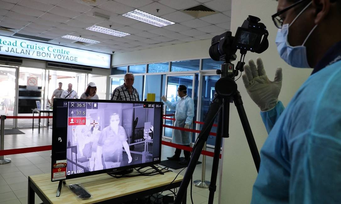 Agente de saúde verifica temperatura de passageiros no terminal de cruzeiros em Port Kiang, na Malásia Foto: Lim Huey Teng / Reuters