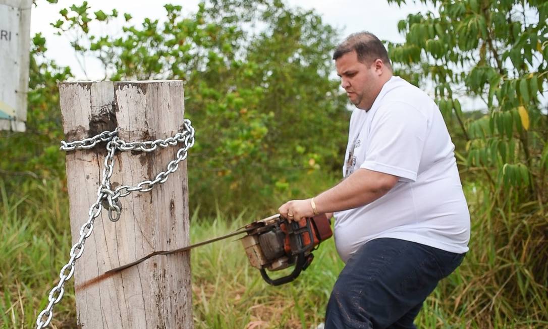 O deputado estadual Jeferson Alves (PTB-RR) serra o tronco e corta a corrente que bloqueava o acesso à BR-174, onde vivem os índios Kinja, na TI Waimiri-Atroari Foto: Divulgação