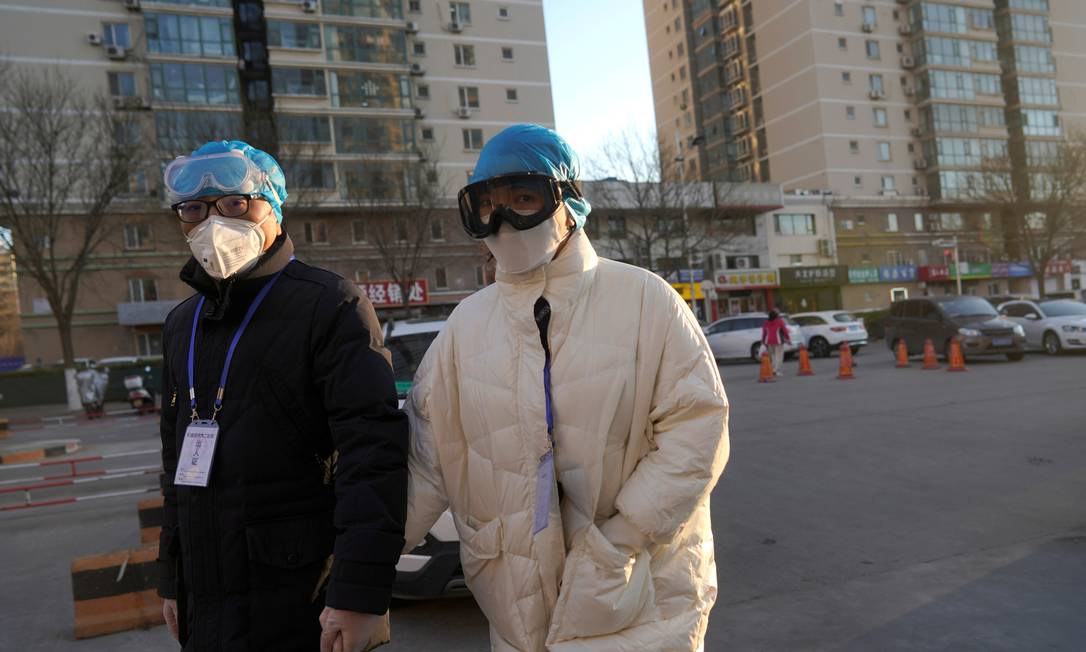 Em Pequim, pessoas usam tocas de plástico, óculos de proteção com máscaras contra o coronavírus Foto: STRINGER / REUTERS