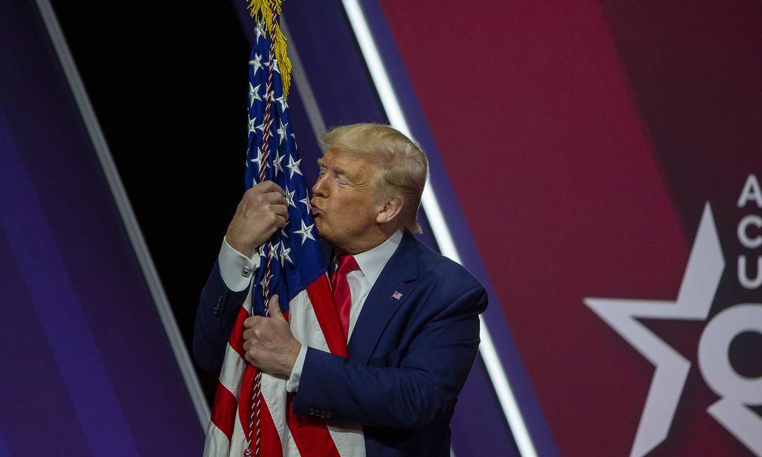 Trump abraça a bandeira americana durante discurso no encontro anual da Conferência de Ação Política Conservadora Foto: TASOS KATOPODIS / AFP