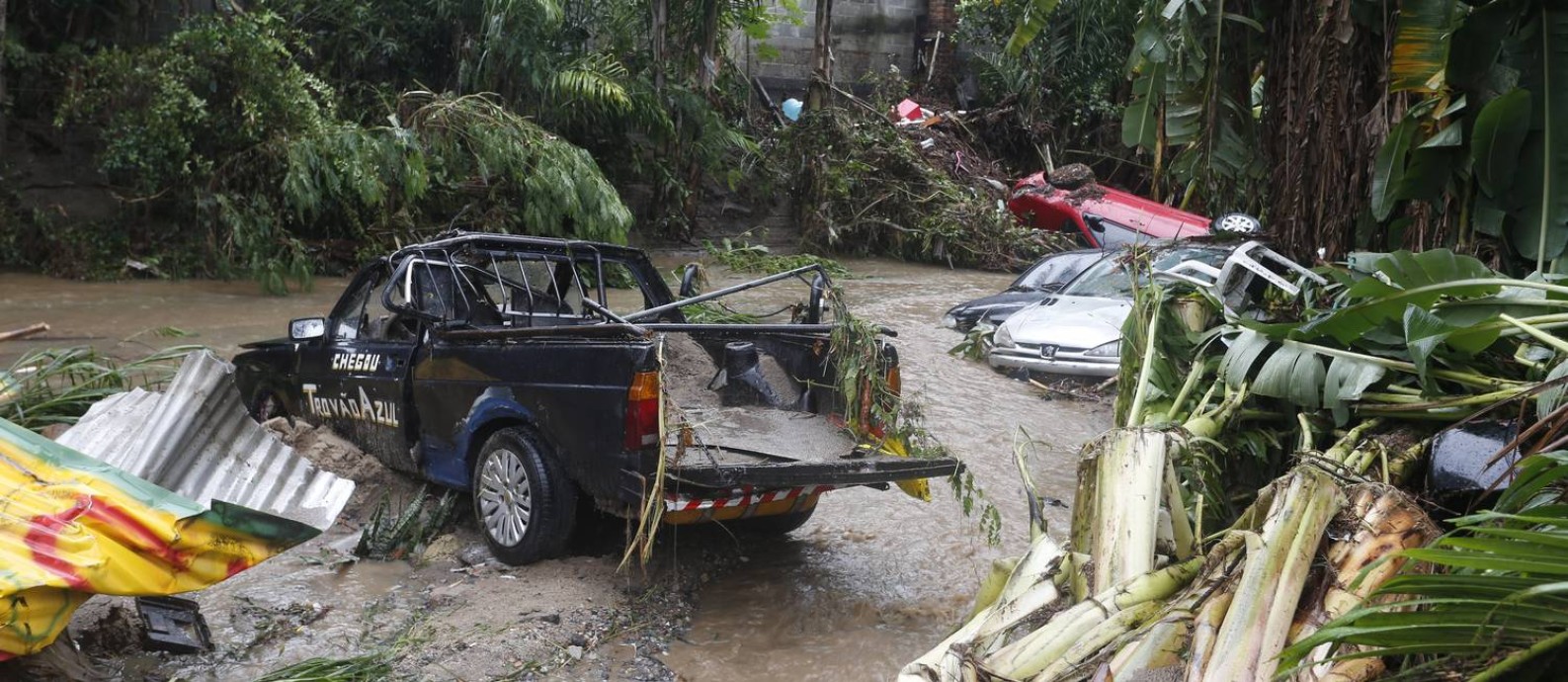 Carros que estavam na Rua São Francisco, em Realengo, são arrastados para um rio durante o temporal Foto: Fabiano Rocha / Agência O Globo