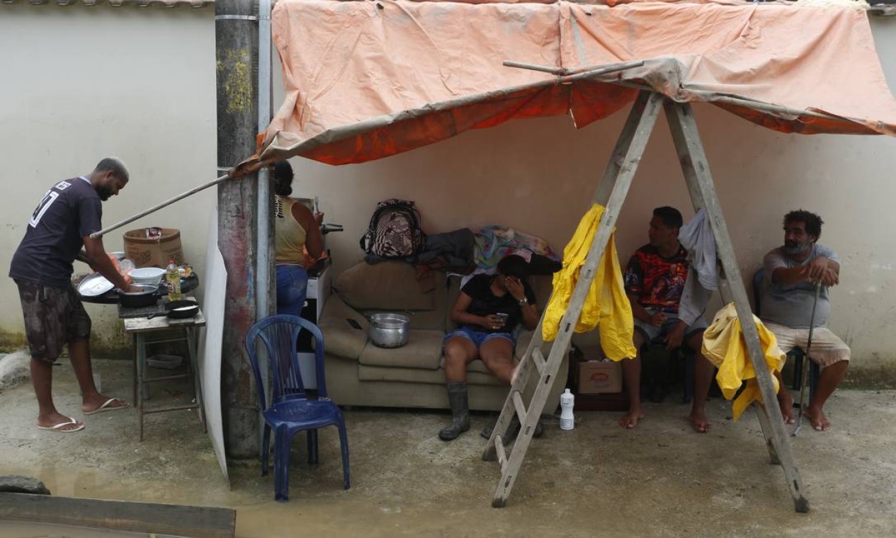 Moradores improvisam cozinha na calçada devido à destruição causada pela chuva Foto: Fabiano Rocha / Agência O Globo