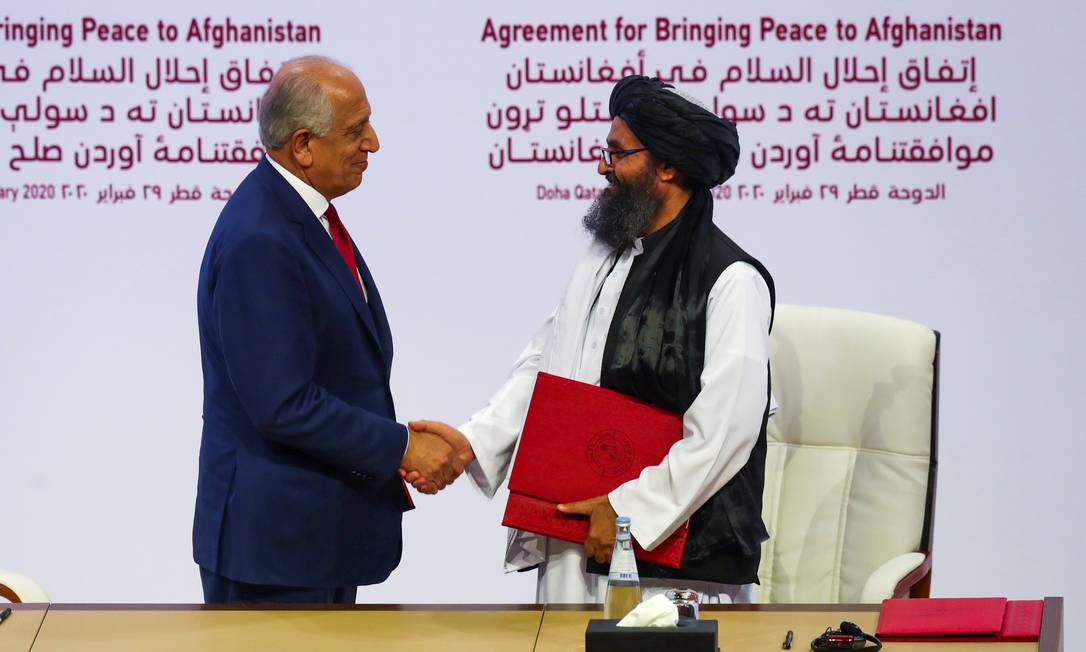 Mulá Abdul Ghani Baradar, líder da delegação talibã, e Zalmay Khalilzad, enviado dos EUA, firmam acordo de paz para o Afeganistão, em Doha Foto: IBRAHEEM AL OMARI / REUTERS/29-02-2020