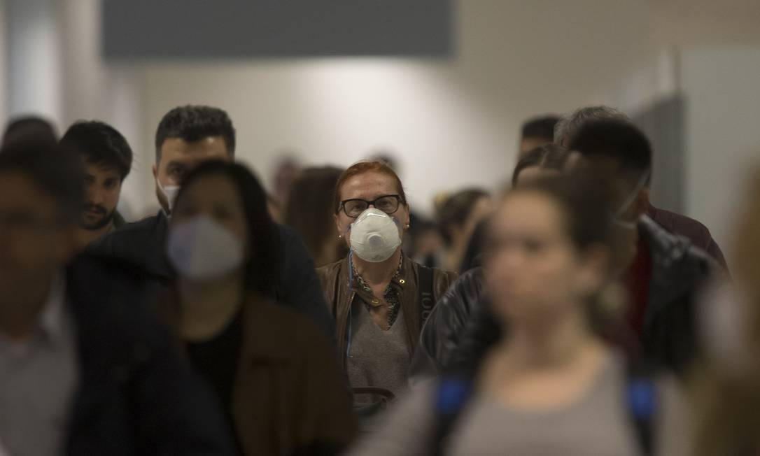 Passageiros usam máscaras no desembarque do aeroporto internacional de Guarulhos: medo de contaminação está levando a cancelamento de viagens Foto: Edilson Dantas/26-020-2020