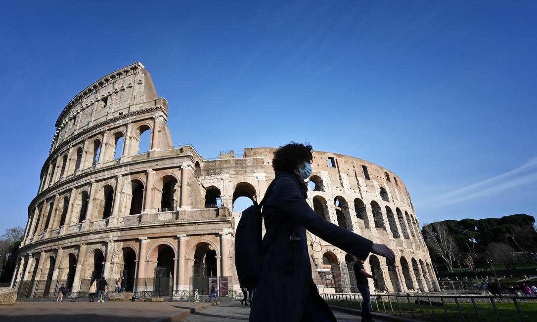 Turista usando máscara para se proteger do coronavírus em frente ao Coliseu, em Roma, que está fechado Foto: ALBERTO PIZZOLI / AFP