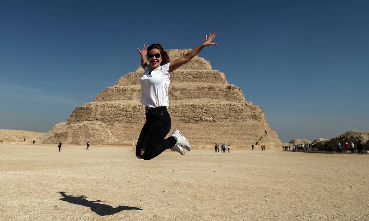 Turista salta para uma foto em frente à pirâmide de Djoser, a mais antiga do mundo, reaberta à visitação no Egito Foto: Mohamed el-Shahed / AFP