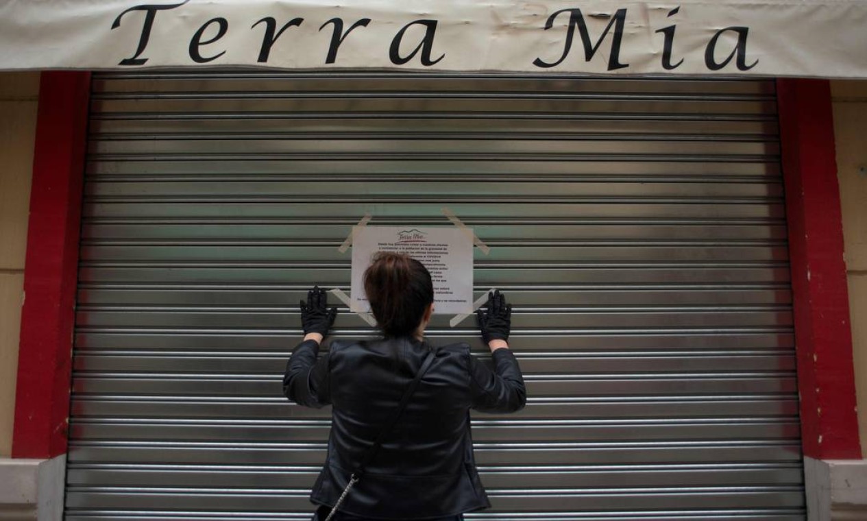 Mulher pendura aviso que seu bar permanecerá fechado no centro de Málaga, no sul da Espanha Foto: Jorge Guerrero / AFP