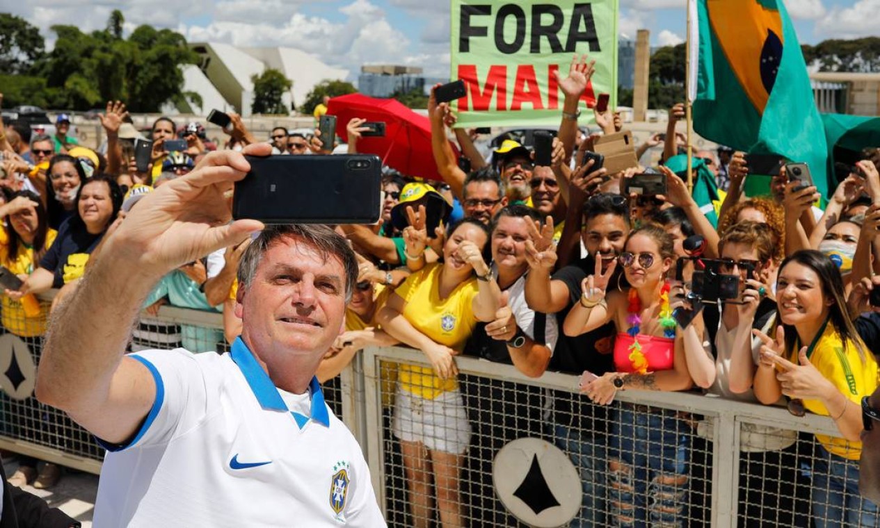 Presidente Jair Bolsonaro cumprimenta seus apoiadores durante manifestação em Brasília. Ele deveria estar em isolamento social por ter tido contato com pelo menos 10 membros de sua equipe. Compartilhar equipamentos, como celulares, também vai de encontro às recomendações por propiciar a contaminação Foto: SERGIO LIMA / AFP