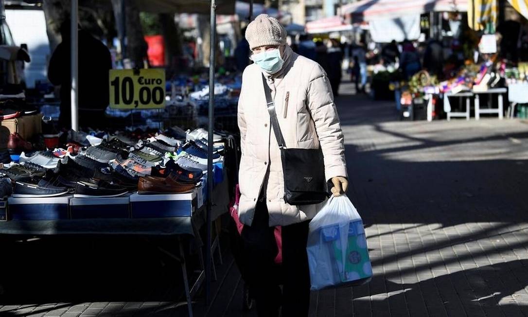 Imagem rara na Itália: mulher retorna do supermercado com máscara em ruas desertas de Milão Foto: Flavio Lo Scalzo/Reuters