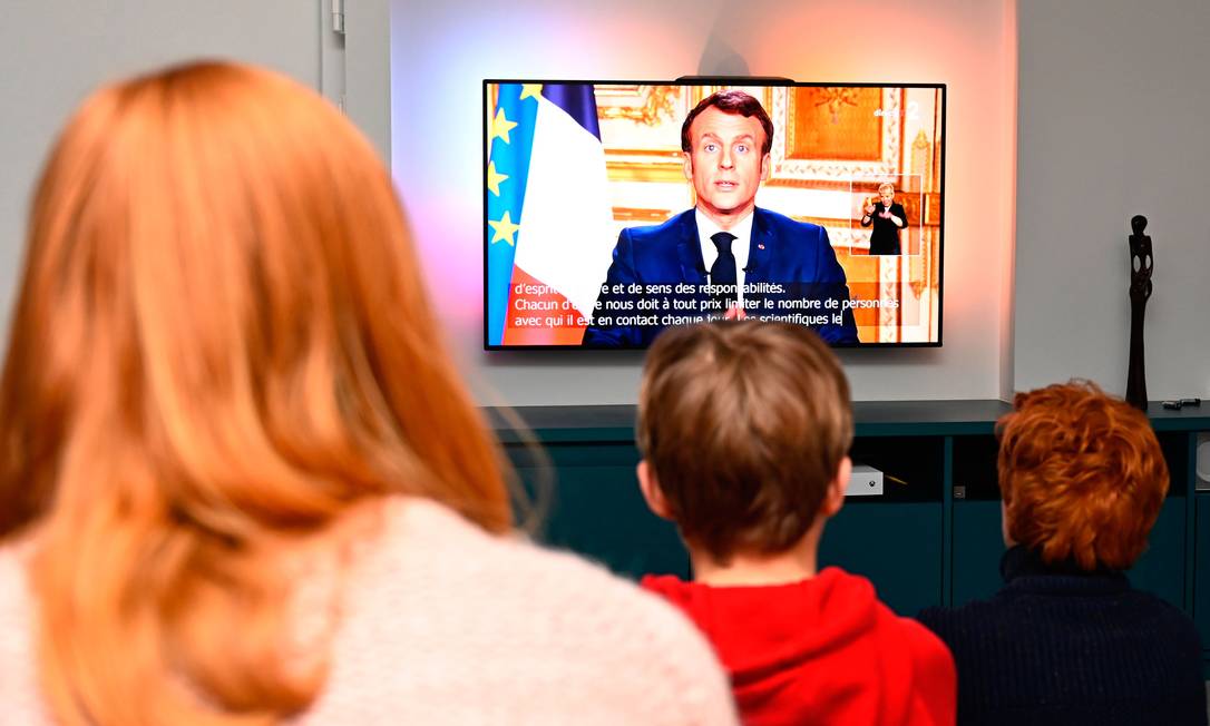 Família assiste discurso em rede nacional do presidente da França, Emmanuel Macron, na cidade de Rennes, na França Foto: DAMIEN MEYER / AFP