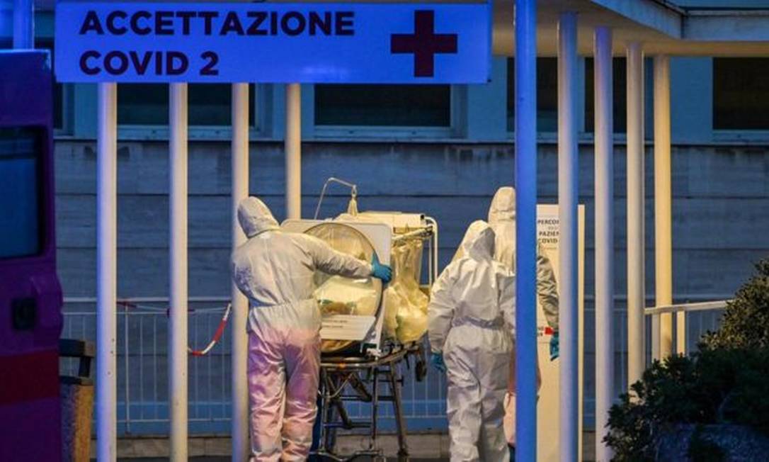 Em Roma, profissionais de saúde carregam paciente em tratamento intensivo para um hospital recém-construído destinado a pessoas com covid-19 Foto: ANDREAS SOLARO/AFP