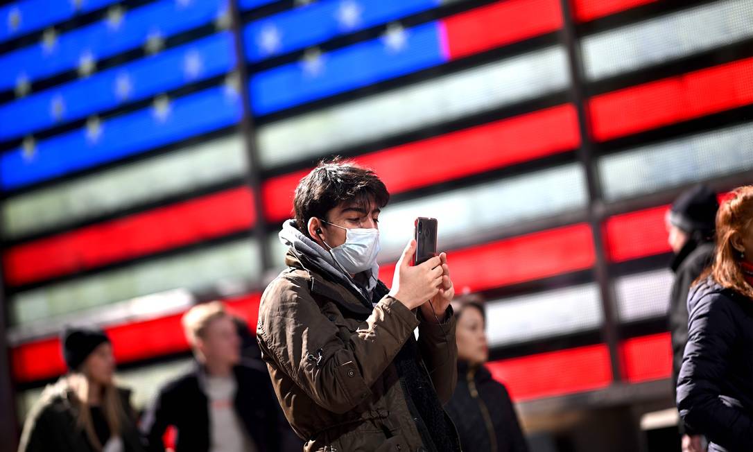 Homem de máscara usa telefone na Times Square, em Nova York Foto: JOHANNES EISELE / AFP