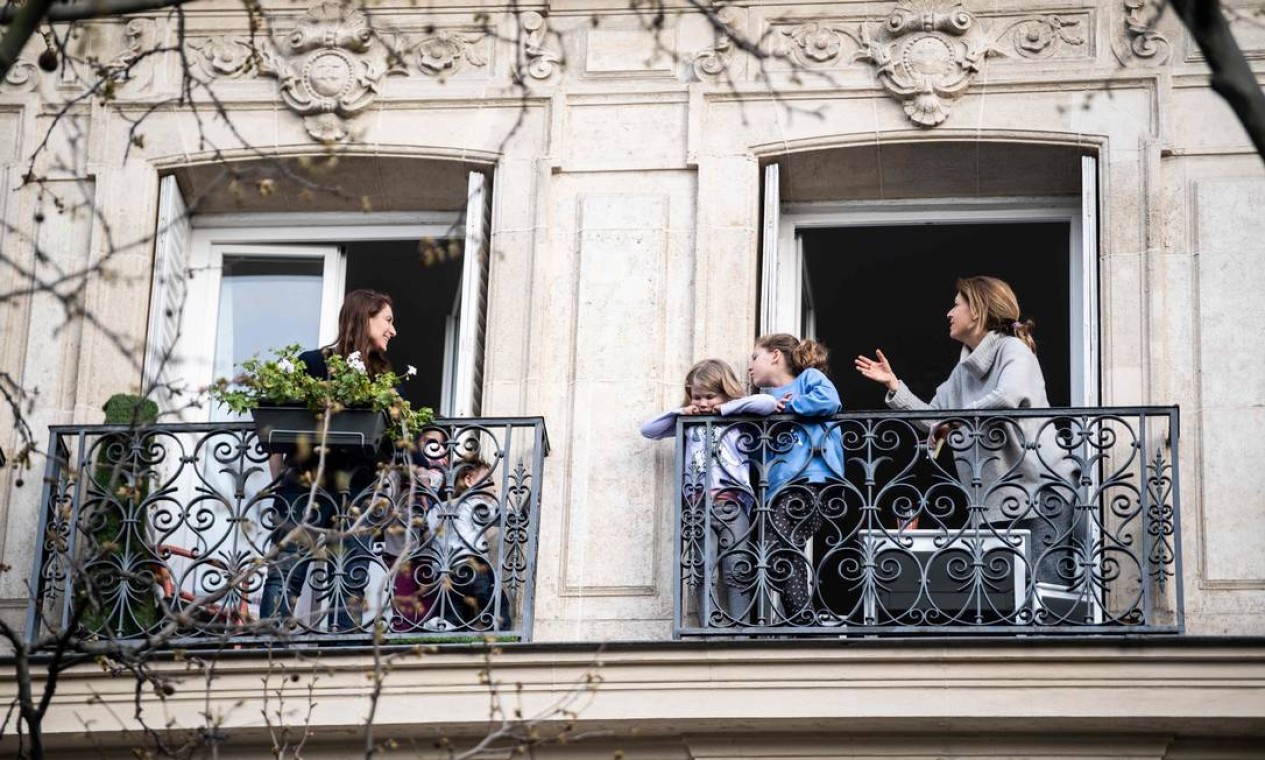 Vizinhos conversam um com os outros de suas varandas em Paris, na última quinta-feira Foto: MARTIN BUREAU / AFP