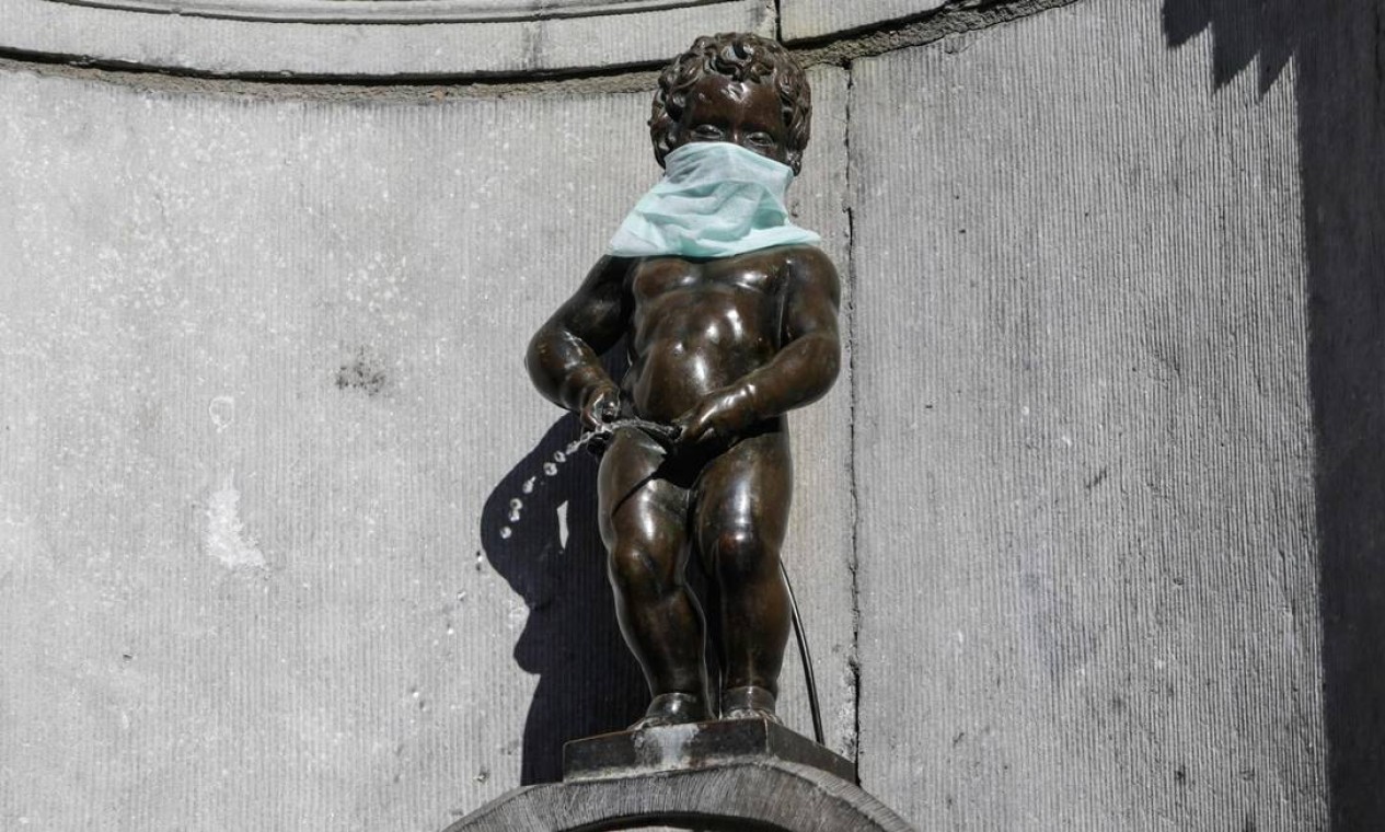 Estátua de Manneken-Pis, com máscara protetora, em Bruxelas, Bélgica Foto: ARIS OIKONOMOU / AFP