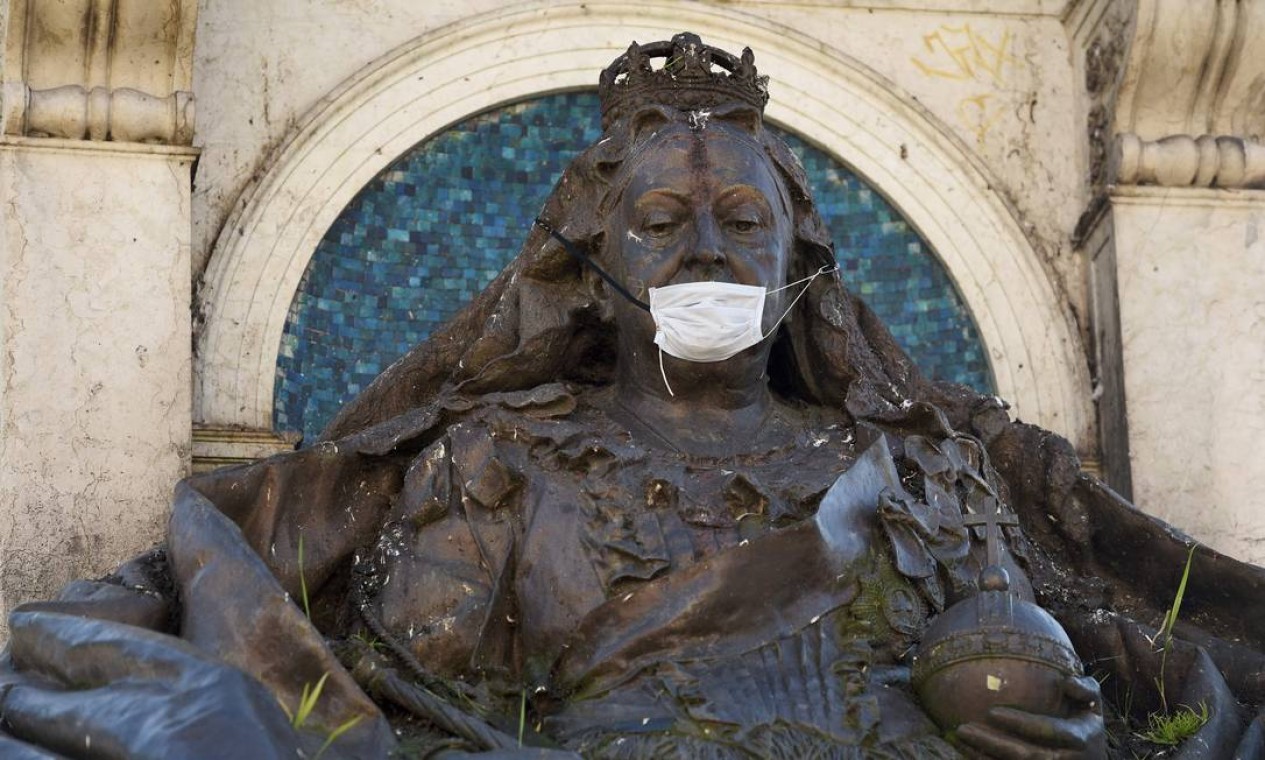 Máscara usada como precaução contra a nova pandemia de coronavírusfoi colocada na estátua da rainha Victoria, em Piccadilly Gardens, Manchester, norte da Inglaterra Foto: OLI SCARFF / AFP
