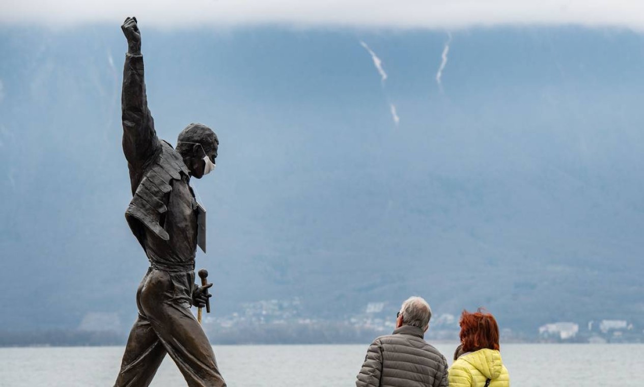 Estátua do falecido cantor Freddie Mercury, adornada com uma máscara protetora, nas margens do Lago Genebra, em Montreux Foto: FABRICE COFFRINI / AFP