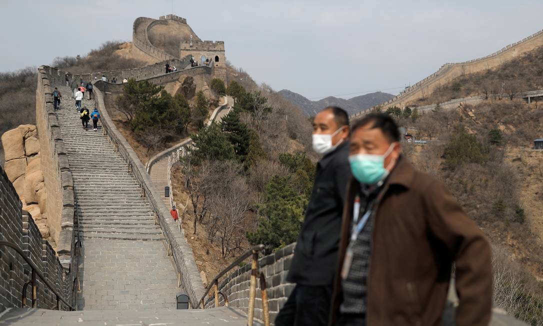 Homens de máscara no trecho da Grande Muralha da China reaberto aos turistas Foto: Thomas Peter / Reuters