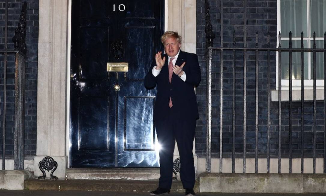 Premier Boris Johnson aplaude médicos no exterior da residência do governo britânico, na rua Downing Foto: HANNAH MCKAY / REUTERS