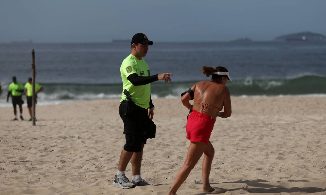 PMs fiscalizam e retiram pessoas da faixa de areia em Copacabana. A polícia avisa que pode prender em caso de persistência Foto: Fabio Motta / Agência O Globo
