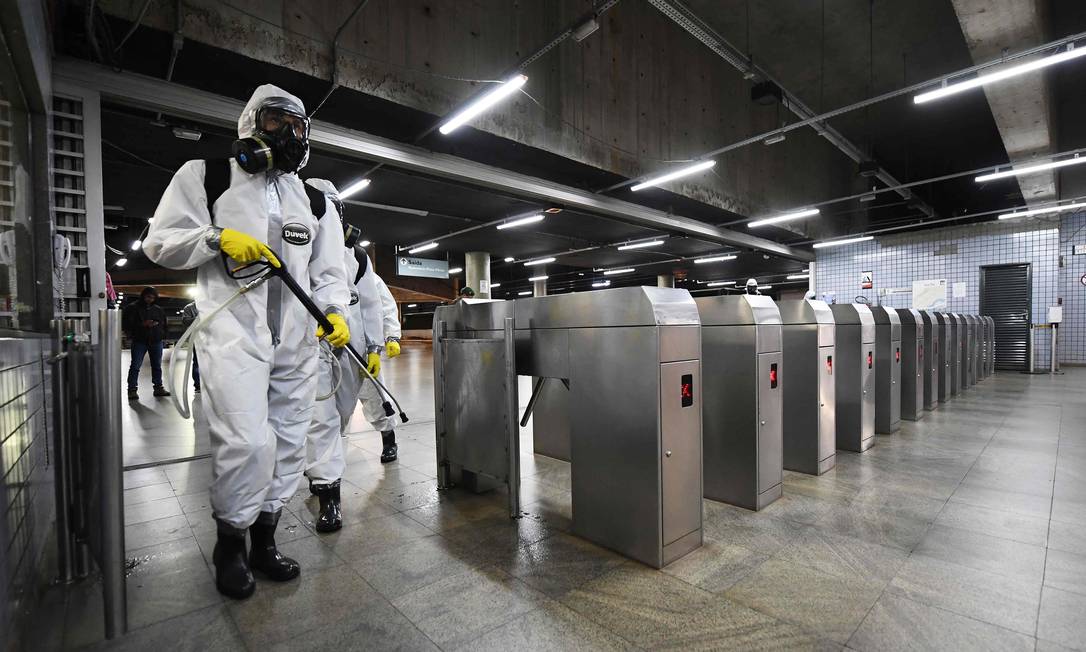 Membros das forças armadas usam roupas de proteção contra o coronavírus para desinfectar uma estação de metrô em Brasília. Foto: EVARISTO SA / AFP