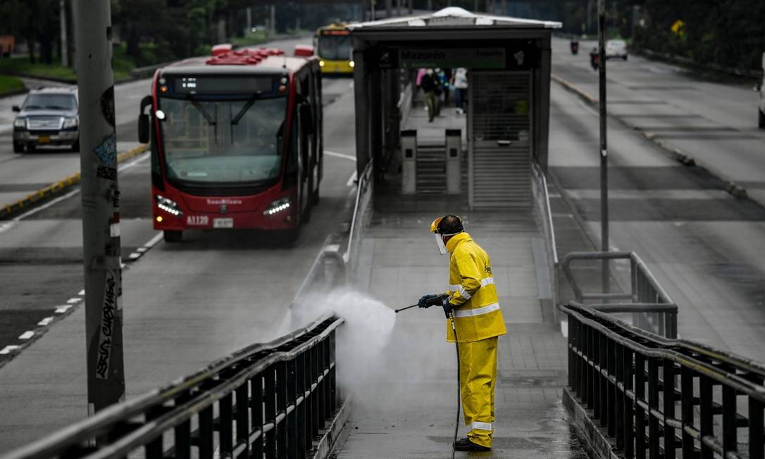Homem desinfeta ponto de ônibus em Bogotá Foto: JUAN BARRETO / AFP / 28-03-2020