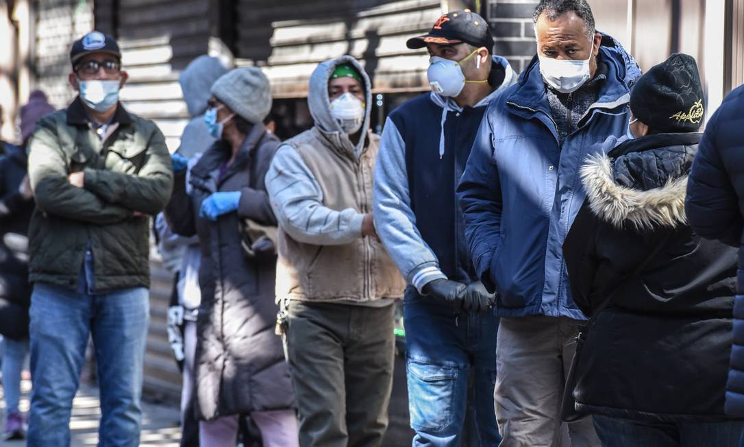 Pessoas aguardam em fila de mercado com máscaras de proteção na cidade de Nova York, a mais afetada nos Estados Unidos, o novo epicentro global da Covid-19 Foto: STEPHANIE KEITH / AFP
