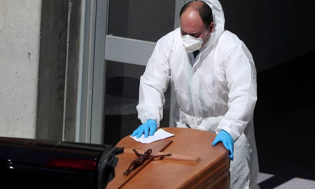 Agente funerário carrega caixão de pessoa morta pelo Covid-19 Foto: Susana Vera/Reuters