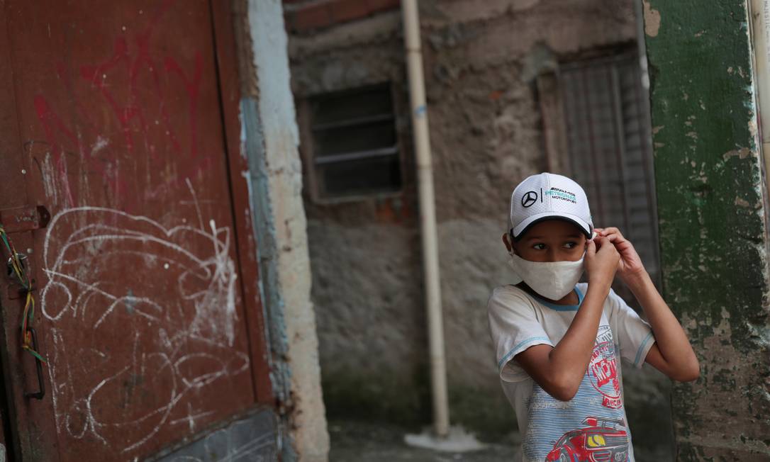 Criança ajusta máscara de proteção contra o coronavírus na favela de Paraisópolis, em São Paulo, uma das maiores do país Foto: AMANDA PEROBELLI / REUTERS