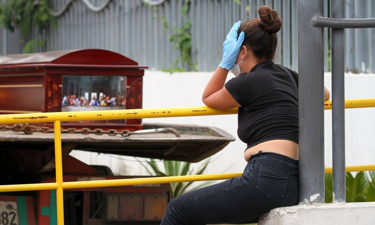 Uma mulher usando máscara facial e luvas chora enquanto aguarda o cadáver de um parente diante de um hospital em Guayaquil Foto: ENRIQUE ORTIZ / AFP