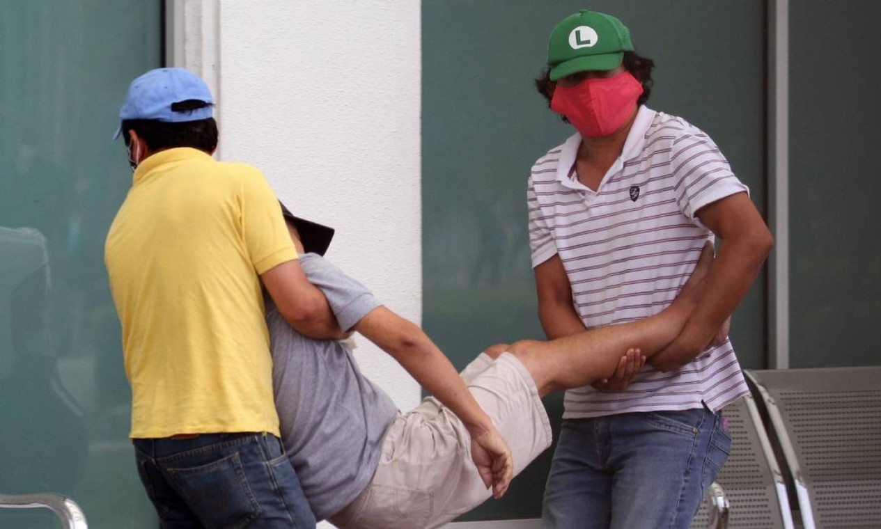 Homens transportam um homem doente para um hospital em Guayaquil Foto: ENRIQUE ORTIZ / AFP