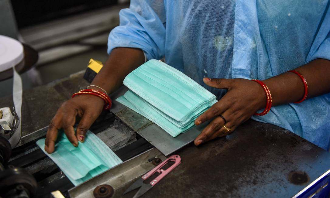Trabalhador prepara máscaras faciais em linha de montagem na Índia Foto: SAM PANTHAKY / AFP