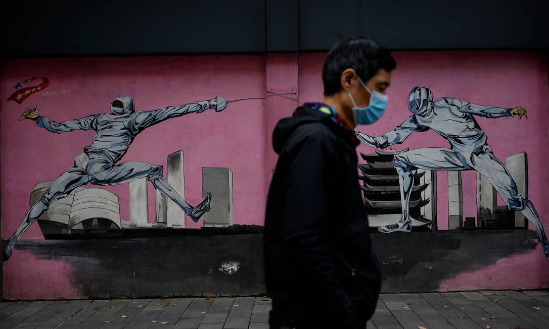 Homem com máscara facial caminha por Wuhan, na China Foto: NOEL CELIS / AFP